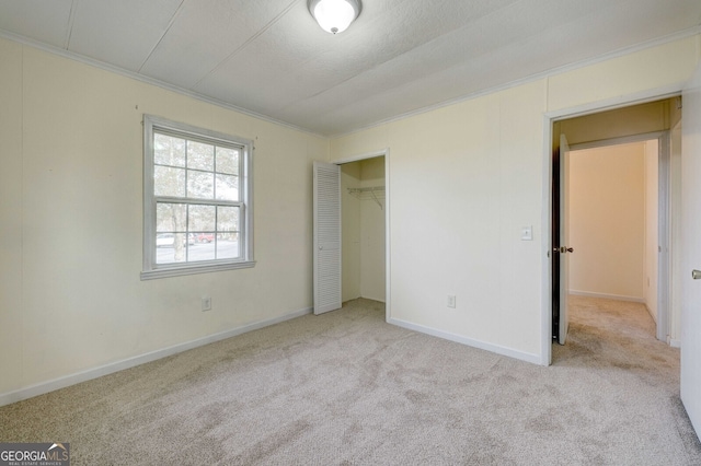 unfurnished bedroom featuring light carpet, crown molding, a closet, and a textured ceiling