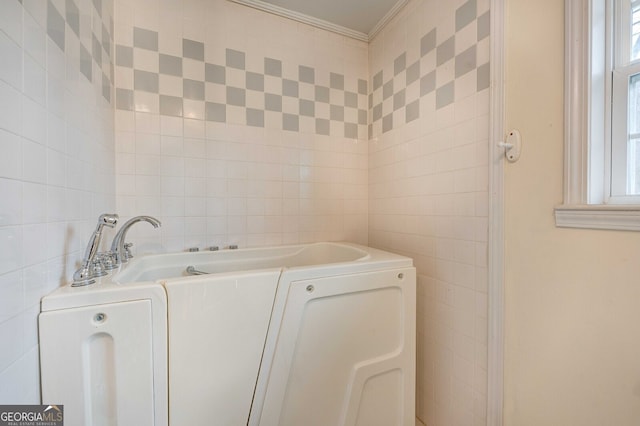 bathroom with tile walls, crown molding, and a tub