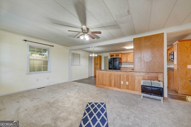 unfurnished living room featuring ornamental molding, carpet flooring, ceiling fan with notable chandelier, and heating unit