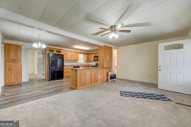 kitchen with heating unit, kitchen peninsula, pendant lighting, light colored carpet, and black appliances