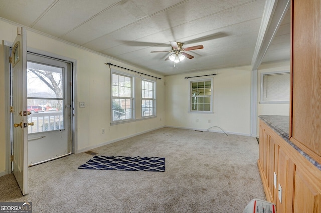 interior space featuring ceiling fan, ornamental molding, and light carpet