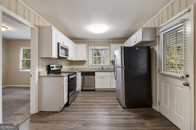 kitchen with appliances with stainless steel finishes, dark hardwood / wood-style floors, white cabinets, and dark stone counters