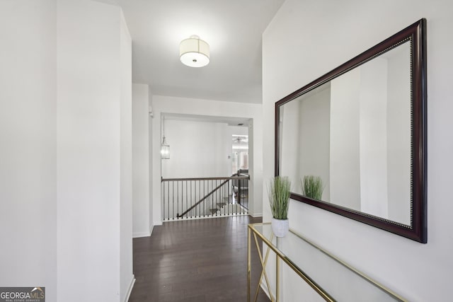 hallway with dark wood-style floors, an upstairs landing, and baseboards