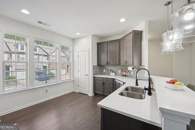 kitchen featuring pendant lighting, sink, backsplash, dark wood-type flooring, and dark brown cabinets