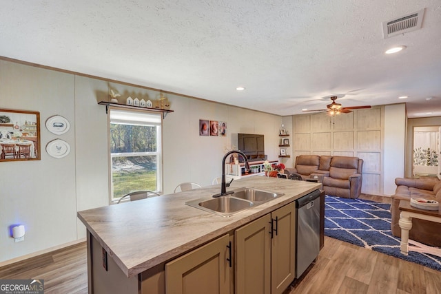 kitchen featuring dishwasher, a kitchen island with sink, sink, and a textured ceiling