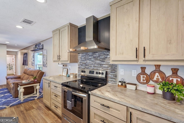 kitchen with light brown cabinets, electric range, a textured ceiling, and wall chimney range hood