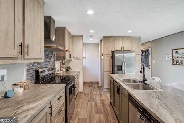 kitchen with wall chimney range hood, sink, light hardwood / wood-style flooring, stainless steel appliances, and light brown cabinetry