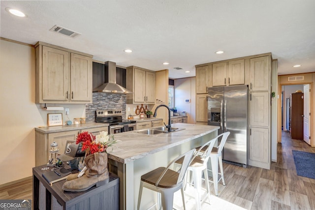 kitchen with sink, a breakfast bar area, light hardwood / wood-style floors, stainless steel appliances, and wall chimney range hood