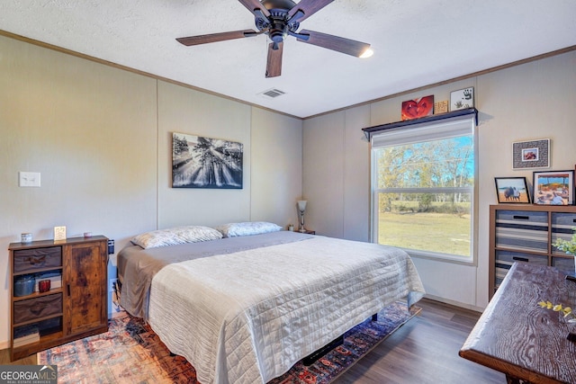 bedroom featuring multiple windows, dark hardwood / wood-style flooring, a textured ceiling, and ceiling fan