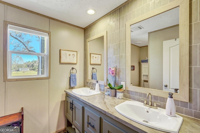 bathroom with decorative backsplash, vanity, a textured ceiling, and ornamental molding