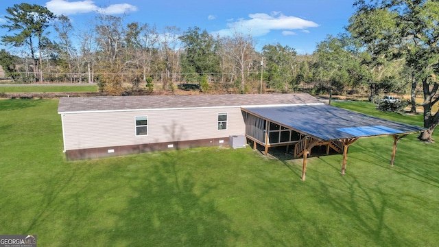 rear view of house featuring cooling unit, a lawn, and a sunroom