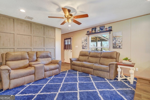 living room with ornamental molding, dark wood-type flooring, ceiling fan, and a textured ceiling