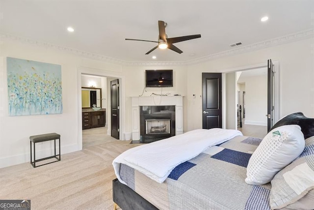 bedroom featuring crown molding, ceiling fan, ensuite bathroom, and light colored carpet