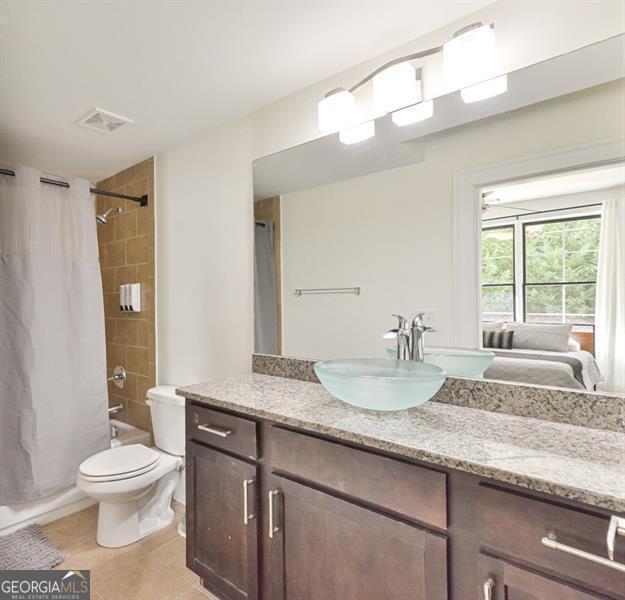 full bathroom with tile patterned flooring, vanity, shower / tub combo, and toilet