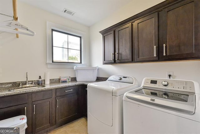 clothes washing area with sink, washing machine and dryer, cabinets, and light tile patterned flooring