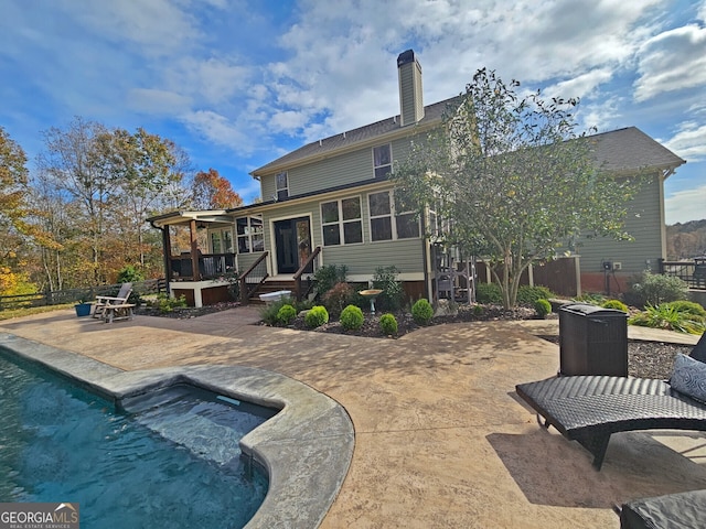 back of house with a sunroom, a pool with hot tub, and a patio area