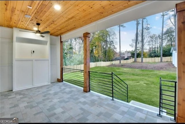 unfurnished sunroom with wood ceiling, ceiling fan, and a wealth of natural light