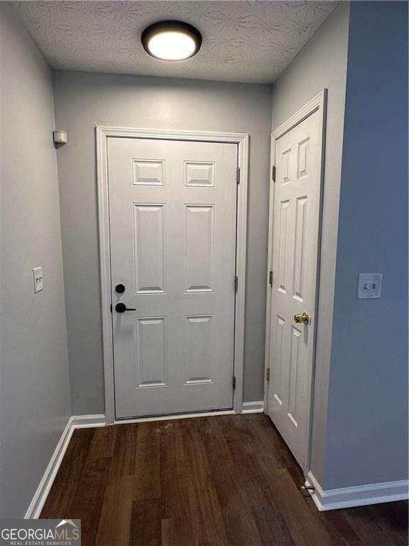 doorway featuring dark hardwood / wood-style flooring and a textured ceiling