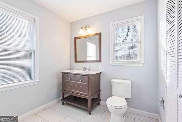 bathroom with vanity, toilet, tile patterned flooring, and a wealth of natural light