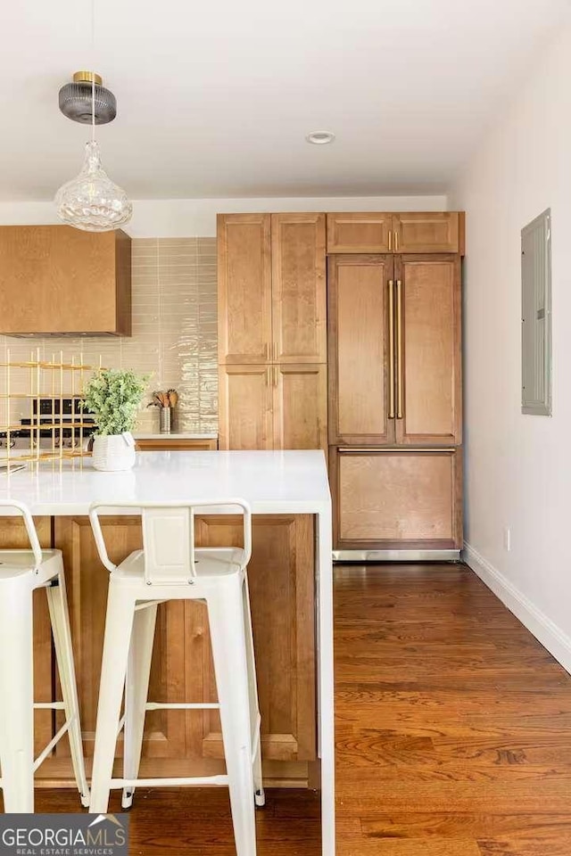 kitchen featuring pendant lighting, a kitchen breakfast bar, dark hardwood / wood-style floors, electric panel, and decorative backsplash