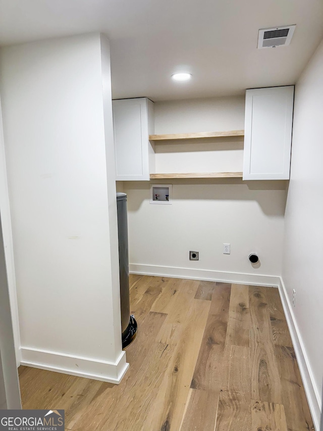 laundry room with electric dryer hookup, hookup for a washing machine, light hardwood / wood-style flooring, and cabinets