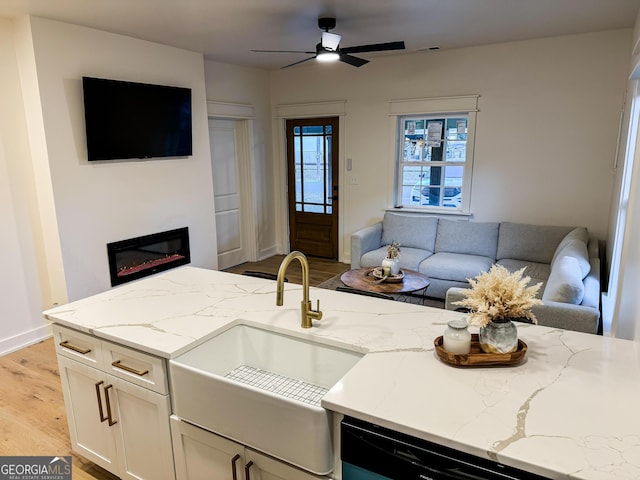 kitchen with sink, ceiling fan, light stone counters, light hardwood / wood-style floors, and white cabinets