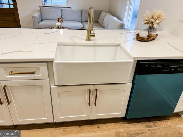 kitchen featuring light stone counters, dishwashing machine, sink, and white cabinets