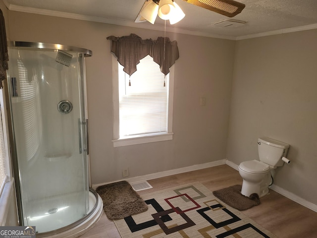 bathroom featuring crown molding, ceiling fan, toilet, and an enclosed shower