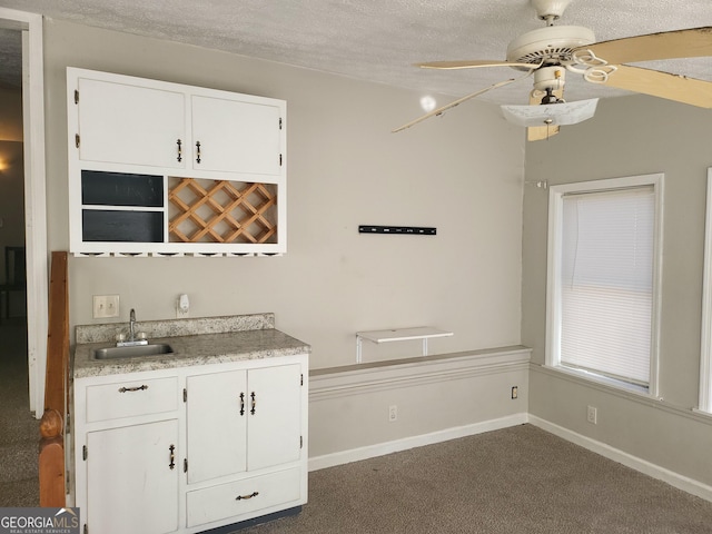 bar with sink, ceiling fan, white cabinetry, a textured ceiling, and dark carpet