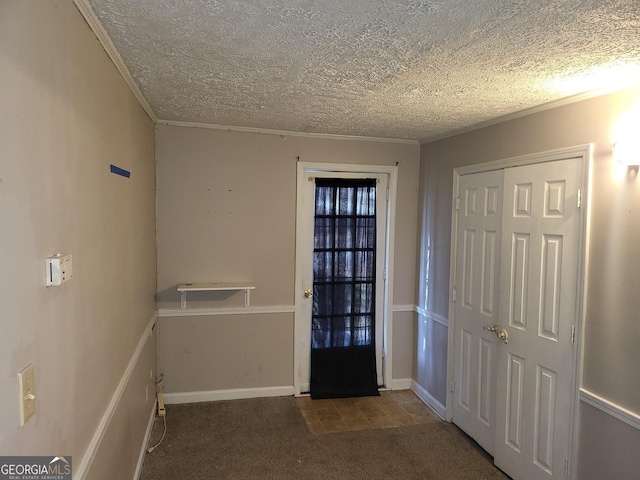 carpeted entryway with ornamental molding and a textured ceiling