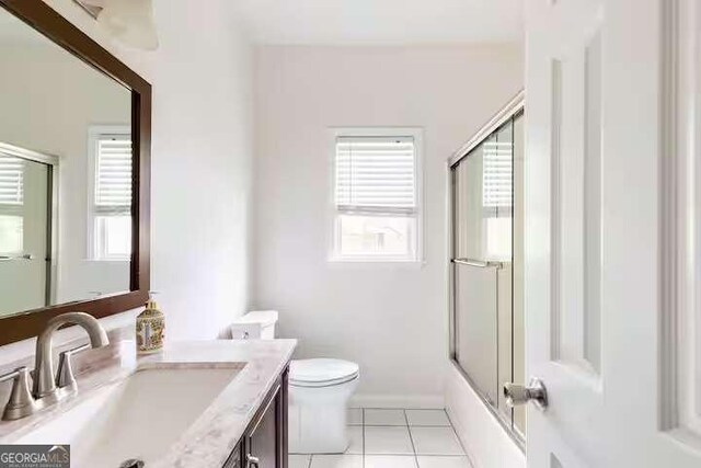 full bathroom featuring tile patterned flooring, vanity, bath / shower combo with glass door, and toilet