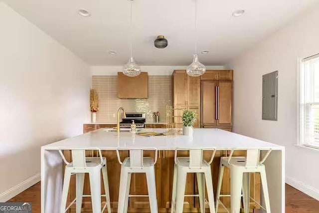 kitchen with sink, electric panel, dark hardwood / wood-style floors, a spacious island, and a kitchen bar