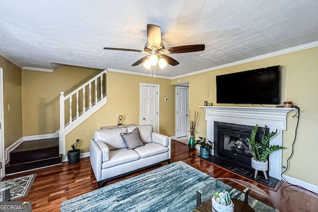 living room with ornamental molding, dark hardwood / wood-style floors, ceiling fan, and a textured ceiling