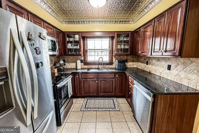 kitchen with stainless steel appliances, light tile patterned flooring, sink, and decorative backsplash