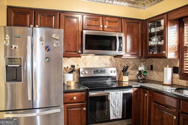 kitchen with stainless steel appliances, dark stone countertops, and decorative backsplash