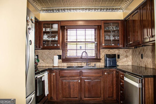 kitchen with appliances with stainless steel finishes, sink, backsplash, and dark brown cabinets