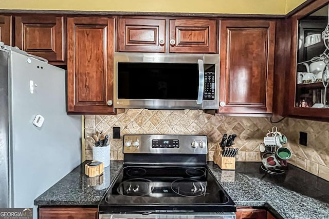 kitchen with stainless steel appliances, decorative backsplash, and dark stone countertops