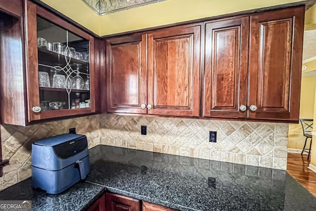 kitchen featuring tasteful backsplash, hardwood / wood-style flooring, and dark stone countertops