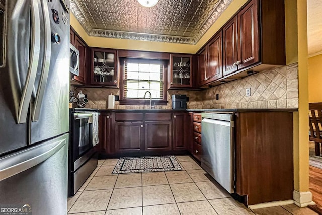 kitchen featuring stainless steel appliances, sink, light tile patterned floors, and backsplash