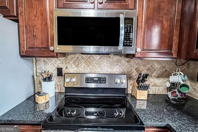 kitchen with tasteful backsplash, appliances with stainless steel finishes, and dark stone countertops