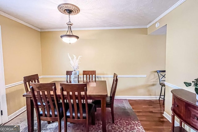 dining space featuring dark hardwood / wood-style flooring, ornamental molding, and a textured ceiling