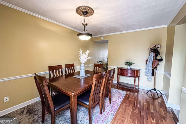 dining room featuring ornamental molding, dark wood-type flooring, and a textured ceiling