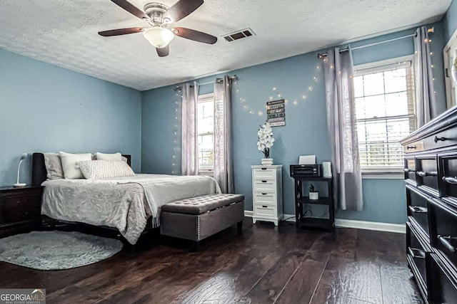 bedroom with ceiling fan, dark hardwood / wood-style flooring, multiple windows, and a textured ceiling