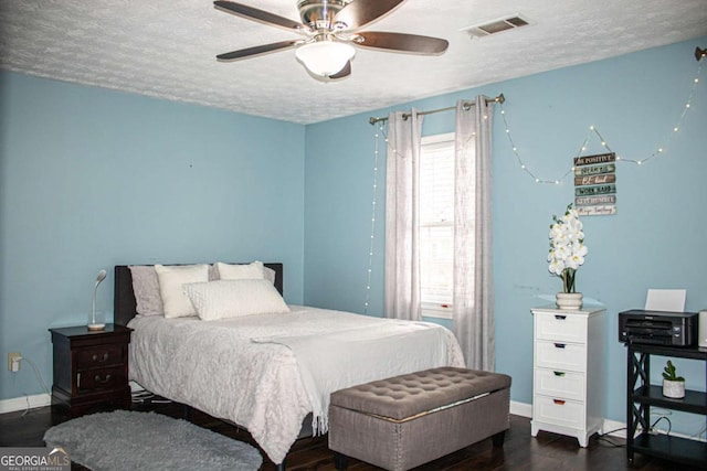 bedroom featuring ceiling fan, dark wood-type flooring, and a textured ceiling