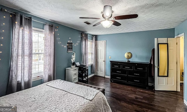 bedroom with ceiling fan, dark hardwood / wood-style floors, and a textured ceiling