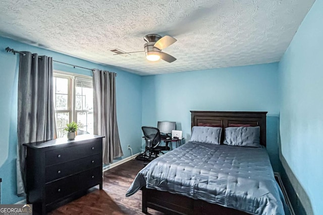 bedroom featuring a textured ceiling, dark wood-type flooring, and ceiling fan