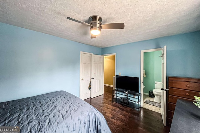 bedroom with ceiling fan, dark wood-type flooring, ensuite bathroom, and a textured ceiling