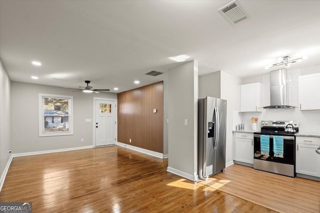 kitchen featuring wall chimney range hood, white cabinetry, stainless steel appliances, light hardwood / wood-style floors, and decorative backsplash