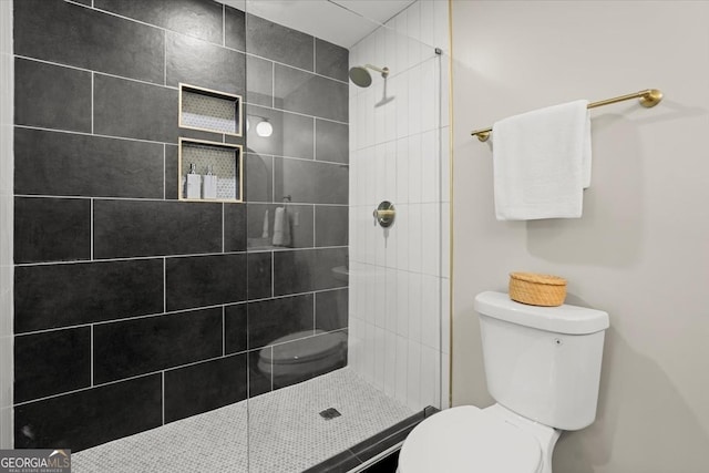 bathroom featuring toilet and a tile shower