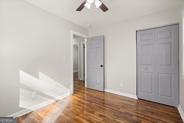 unfurnished bedroom with dark hardwood / wood-style flooring, a closet, and ceiling fan